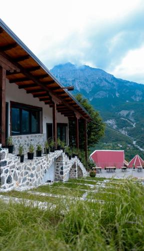 a house with a stone wall and a table in front at Hotel Thethi in Theth