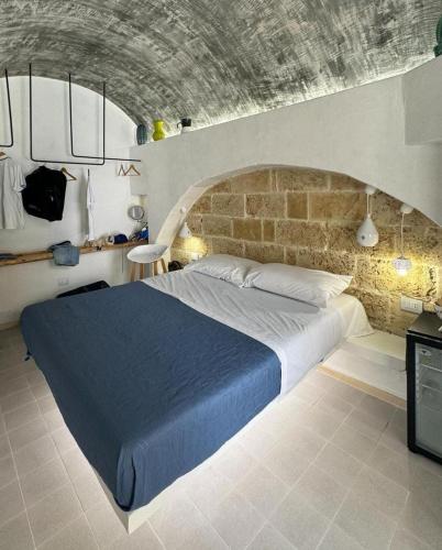 a bedroom with a large bed with a brick wall at Il Pozzo Antico in Gallipoli
