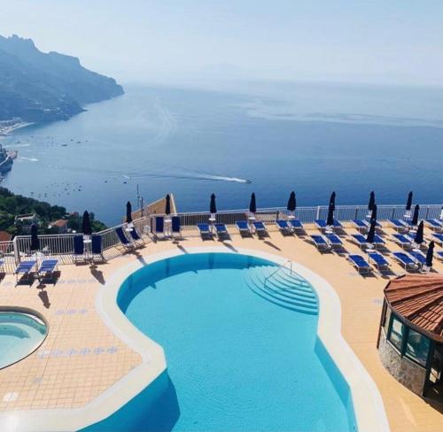 una piscina con sedie e vista sull'oceano di Casa Vacanza Ginevra a Ravello