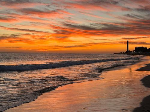 a sunset on the beach with a lighthouse in the background at Casa Las Toro Playa in Chilches