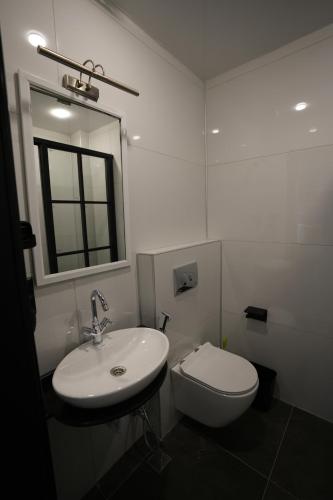 a white bathroom with a toilet and a sink at OLD BaTuMi in Batumi