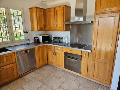 une cuisine avec des armoires en bois et des appareils en acier inoxydable dans l'établissement Belle Maison Familiale 6 ou 8 personnes avec piscine, à Montauroux