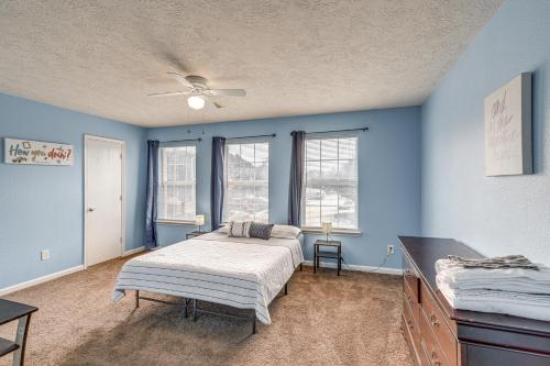 a bedroom with a bed and blue walls and windows at Houston Retreat with Pool Access and Fenced-In Yard! in Houston