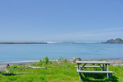 a picnic table sitting on the grass near the water at Smith River Home with Boat Launch and Ocean Views in Smith River