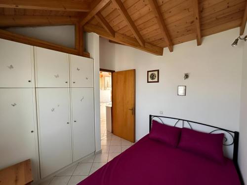 a bedroom with a purple bed and white cabinets at Eva's Apartments in Karlovasi