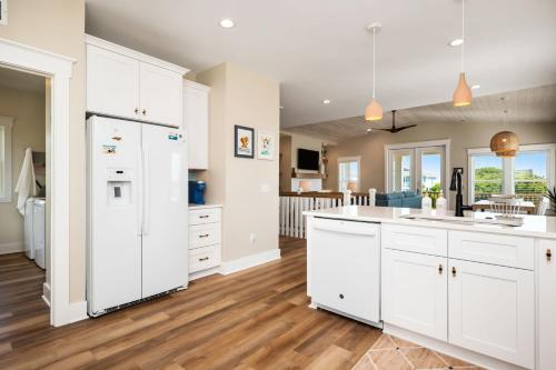 a kitchen with white cabinets and wood floors at All Sands On Deck in Oak Island