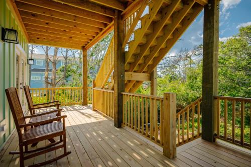 a wooden porch with two chairs on it at All Sands On Deck in Oak Island