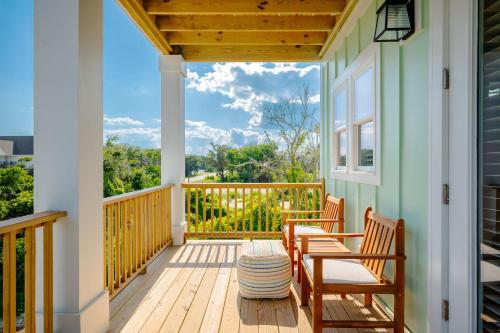 a porch with two chairs and a table with a view at All Sands On Deck in Oak Island