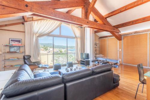 - un salon avec un canapé en cuir et une grande fenêtre dans l'établissement La Panoramique du Port - Welkeys, à Bandol