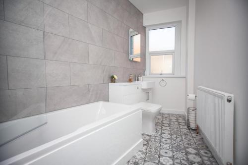 Un baño blanco con bañera y lavabo. en Quayside Quarters, en Weymouth