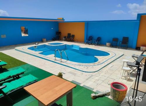 a large swimming pool with a table and chairs at Residencial Oliveira in Porto Novo