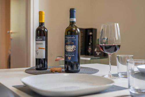 two bottles of wine sitting on a table with a glass at Monolocale Moderno Valpolicella Verona - Jala in San Pietro in Cariano