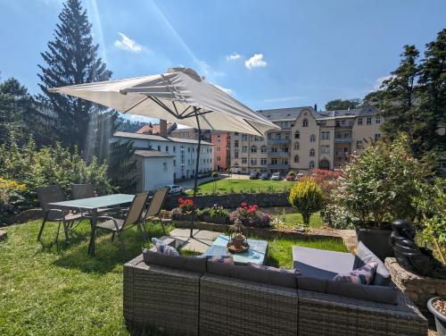 a patio with a table and an umbrella at HW1B - Urlaubsmagie Gemeinschaftsgarten mit Pool, Sauna & Terrasse in Sebnitz
