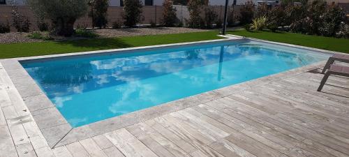 une grande piscine bleue avec une terrasse en bois dans l'établissement Villa Saint Laï 4 chambres 8 personnes, à Lorgues