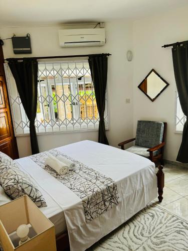 a bedroom with a bed and a chair and a window at D BES Residence Self Catering in Beau Vallon