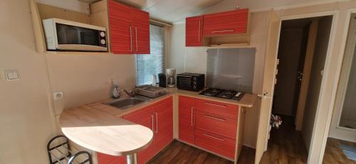 a small kitchen with red cabinets and a sink at MOBIL HOME in Ivry-la-Bataille