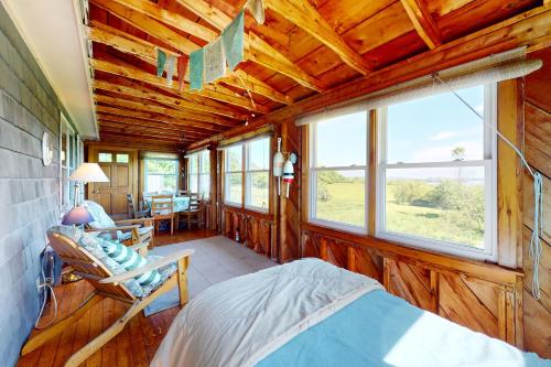 a bedroom with wooden walls and a bed and windows at Lobster Tail Cottage in Castine