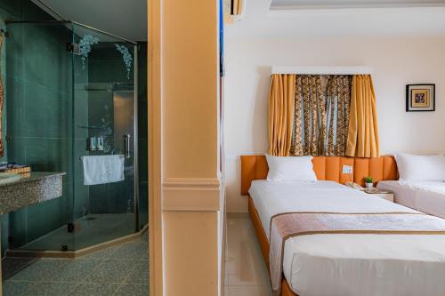 胡志明市的住宿－Fortune 1127 - Central Hotel，一间卧室设有两张床和玻璃淋浴间
