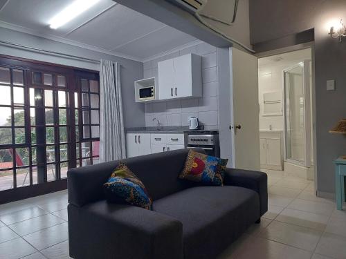 a living room with a couch and a kitchen at Fairway Guest Lodge in Margate