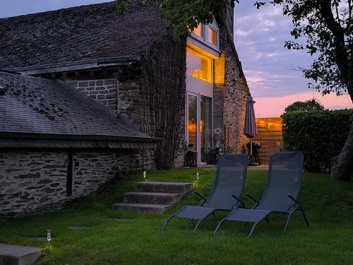 two chairs sitting in the grass in front of a house at Lî Gurni in Houffalize