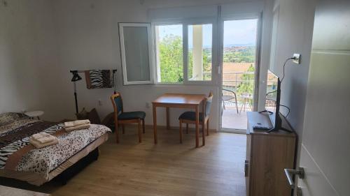 a bedroom with a bed and a table and a balcony at Udobna Soba Sa Prelepim Pogledom #4 in Mladenovac