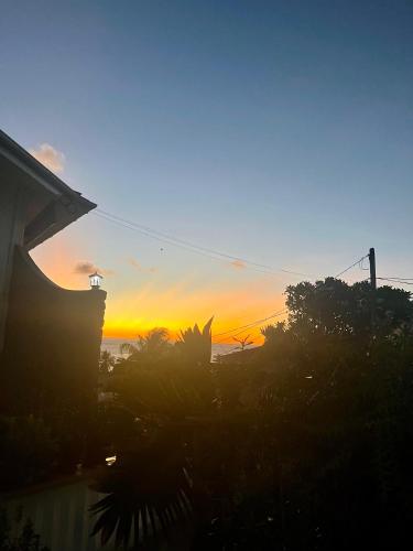 a sunset is seen from a house with plants at D BES Residence Self Catering in Beau Vallon