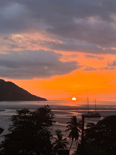 a sunset on the beach with a boat in the water at D BES Residence Self Catering in Beau Vallon