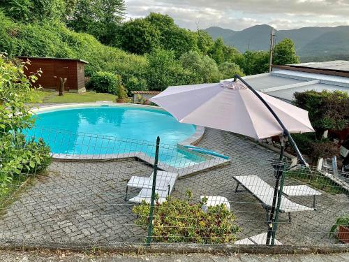 an umbrella and chairs next to a swimming pool at La casa nel verde con piscina in Polverara