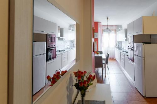 una cocina con electrodomésticos blancos y un jarrón de flores sobre una mesa en appartamento a 50 mt dal mare, en Porto SantʼElpidio