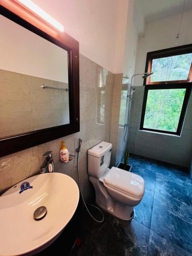 a bathroom with a white toilet and a sink at Rest Full Homestay in Ella