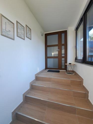 a hallway with a staircase with wooden floors and a door at Apartman LuMa in Gospić