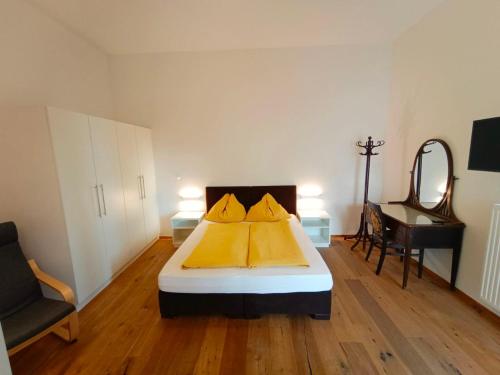 1 dormitorio con 1 cama con sábanas amarillas y espejo en Seeappartements Villa Sole en Pörtschach am Wörthersee
