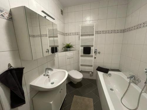 e bagno bianco con lavandino, servizi igienici e vasca. di Ferienwohnung Mia a Niestetal