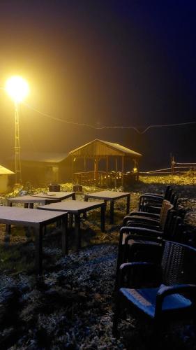 a group of picnic tables with a light at night at Kale-i Bala Palam Cafe Pansiyon in Çamlıhemşin