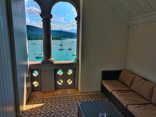 a living room with a couch and a view of the water at Seeappartements Villa Sole in Pörtschach am Wörthersee