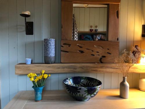 a shelf with a bowl and a vase with flowers at Ardmore House B&B in Lochinver