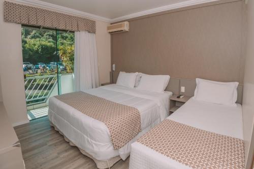 a hotel room with two beds and a window at Itá Thermas Resort e Spa in Itá