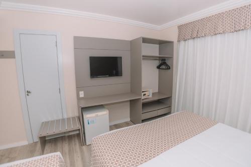 a white bedroom with a bed and a television at Itá Thermas Resort e Spa in Itá
