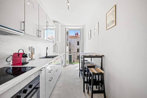 une cuisine avec des armoires blanches et un comptoir avec des tabourets dans l'établissement Appartement F3, 2 chambres, 80m2, à Nice
