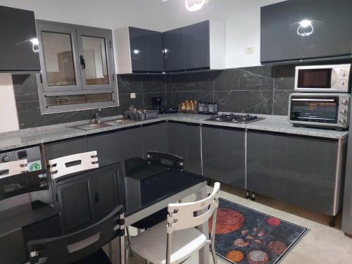 eine Küche mit schwarzen Schränken und einem Herd mit Backofen in der Unterkunft Villa TAGUERMES in Taguermess