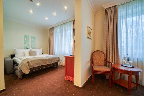 a hotel room with a bed and a chair at Parkhotel Am Glienberg by NP in Zinnowitz
