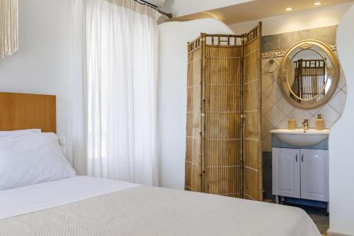 a bedroom with a bed and a sink and a mirror at Aurora Skopelos in Skopelos Town
