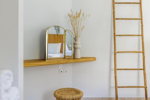 a shelf with a mirror and a vase on a wall at Aurora Skopelos in Skopelos Town