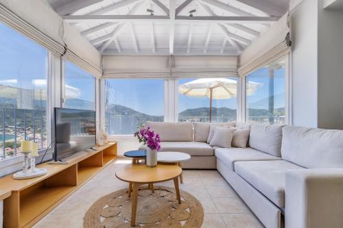 a living room with a white couch and a tv at Aurora Skopelos in Skopelos Town