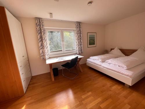 a bedroom with a bed and a desk and a window at Boardinghouse My Maison in Morschen