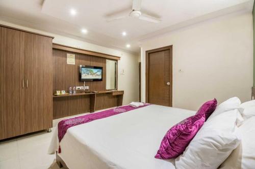 ein Schlafzimmer mit einem großen weißen Bett mit lila Kissen in der Unterkunft Collection O HOTEL MY PLACE HITEX INN in Kondapur