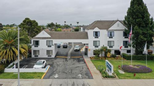 a white house with cars parked in a parking lot at Best Western Surf City in Huntington Beach