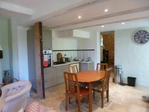 une cuisine et une salle à manger avec une table et des chaises dans l'établissement The Cottage, à Loubès-Bernac