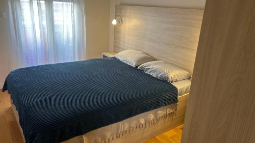 uma cama com um cobertor azul e almofadas em Comfort Central Point apartment em Podgorica