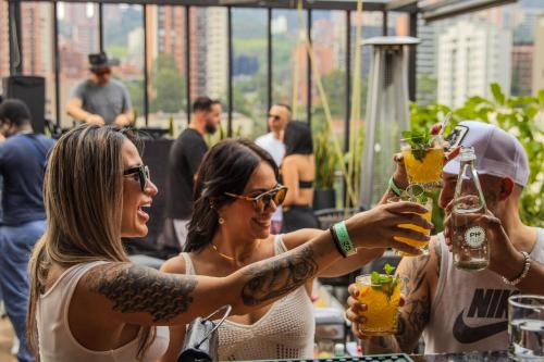two women holding up their drinks at a bar at Haven A Design Hotel in Medellín